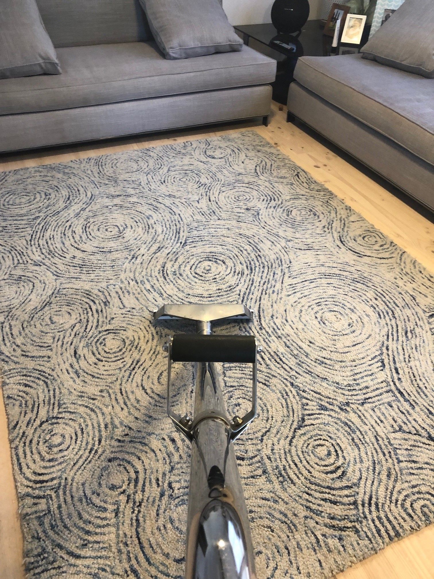 A woman is using a vacuum cleaner to clean a carpet in a living room. A woman is using a vacuum cleaner to clean a carpet in a living room.