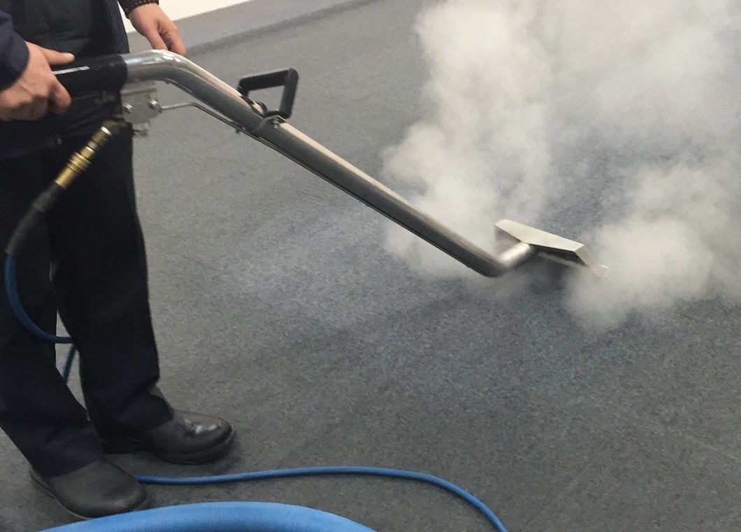 A person is cleaning a carpet with a vacuum cleaner.