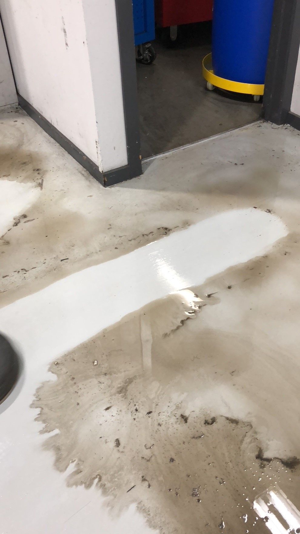 A person is cleaning a dirty floor with a vacuum cleaner.