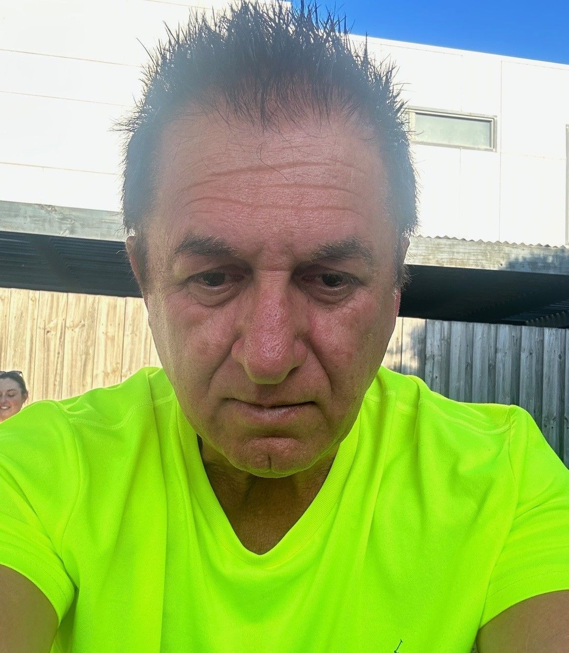 A man in a neon green shirt is taking a selfie.