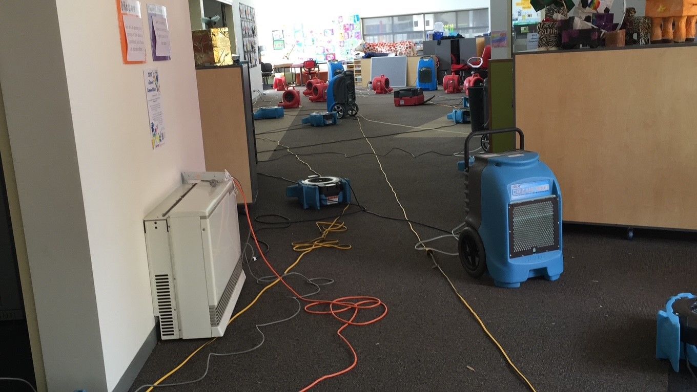 A room with a lot of electrical equipment and fans on the floor.