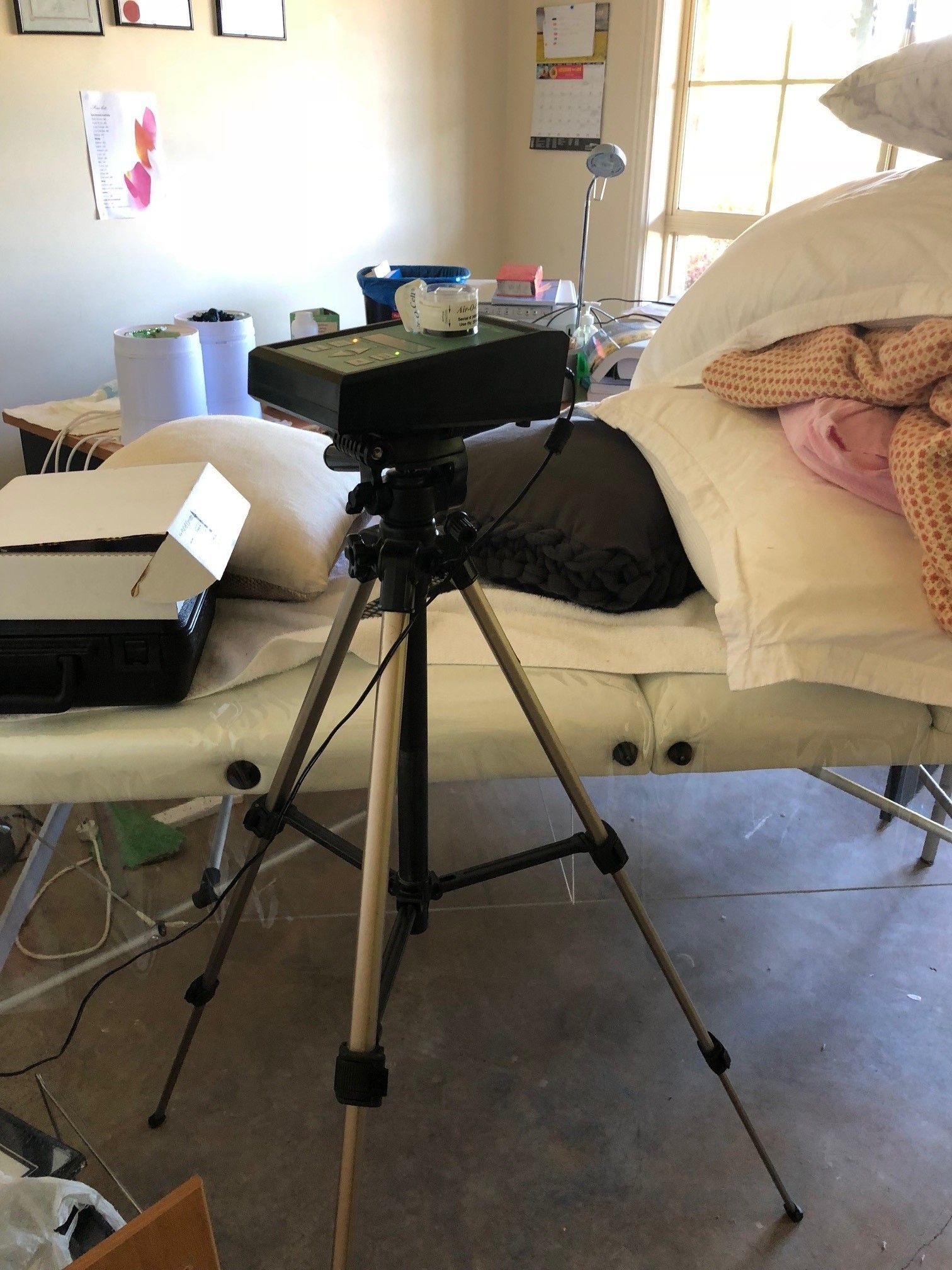 A tripod is sitting on top of a bed in a room.