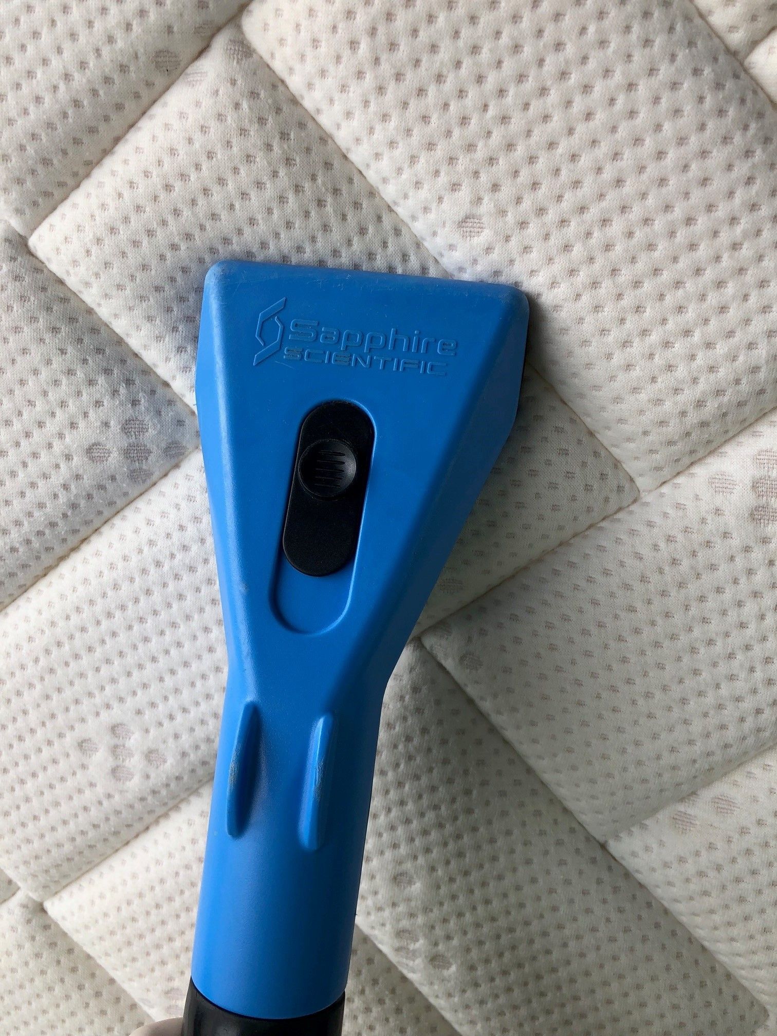 A person is cleaning a mattress with a steam cleaner.