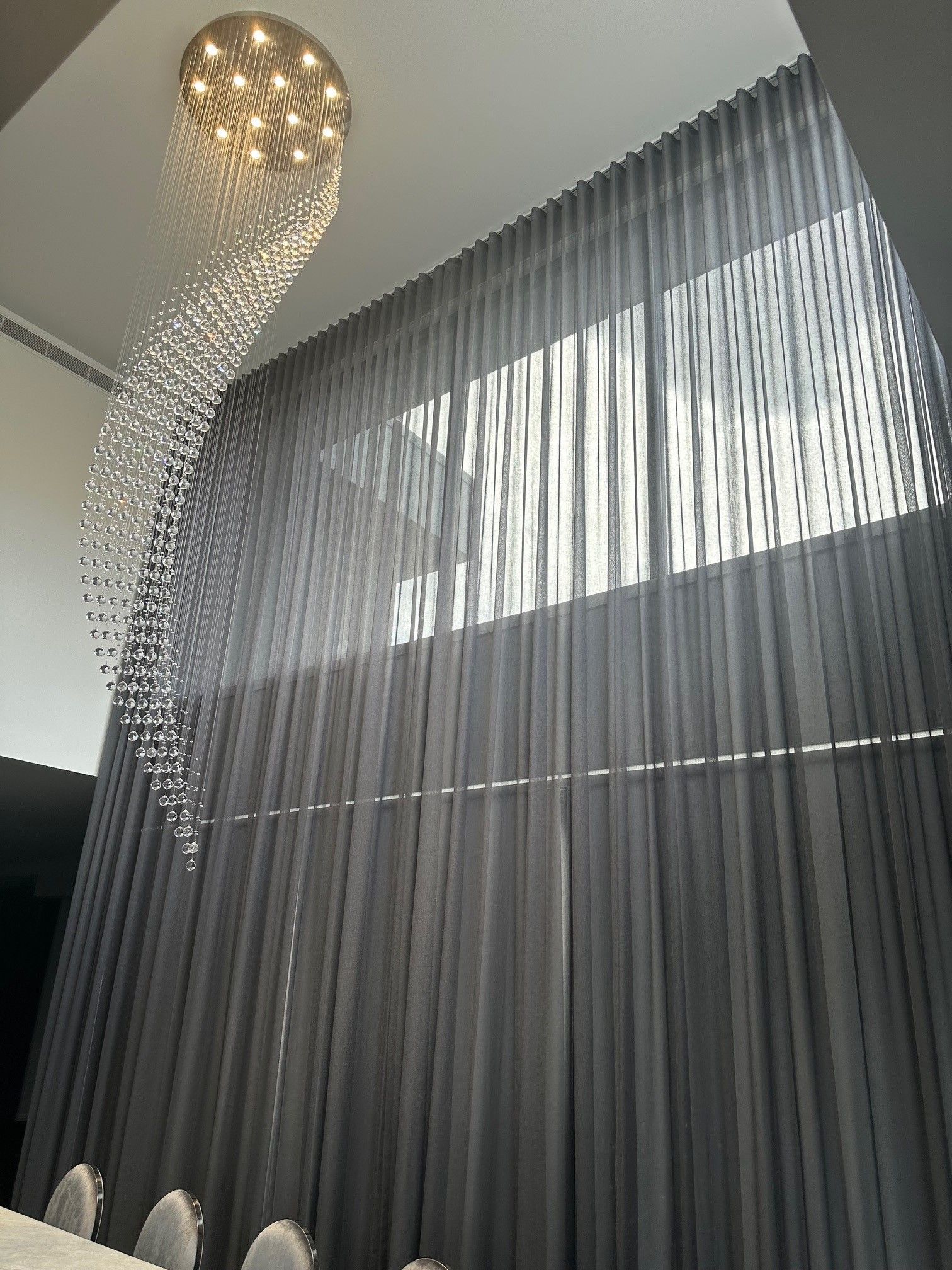 A person wearing pink gloves is cleaning blinds with a brush.