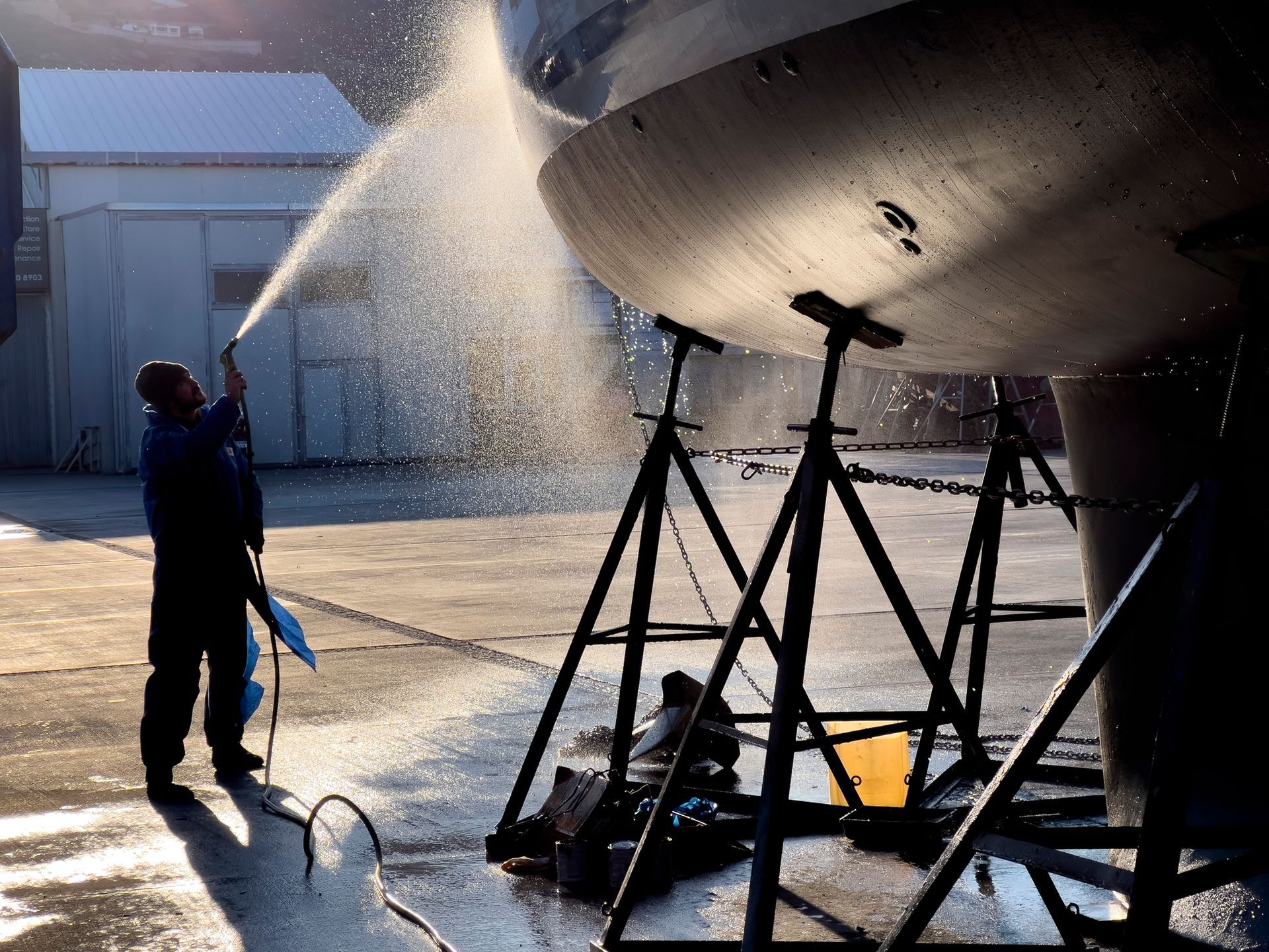 A man is spraying water on a boat in a hangar