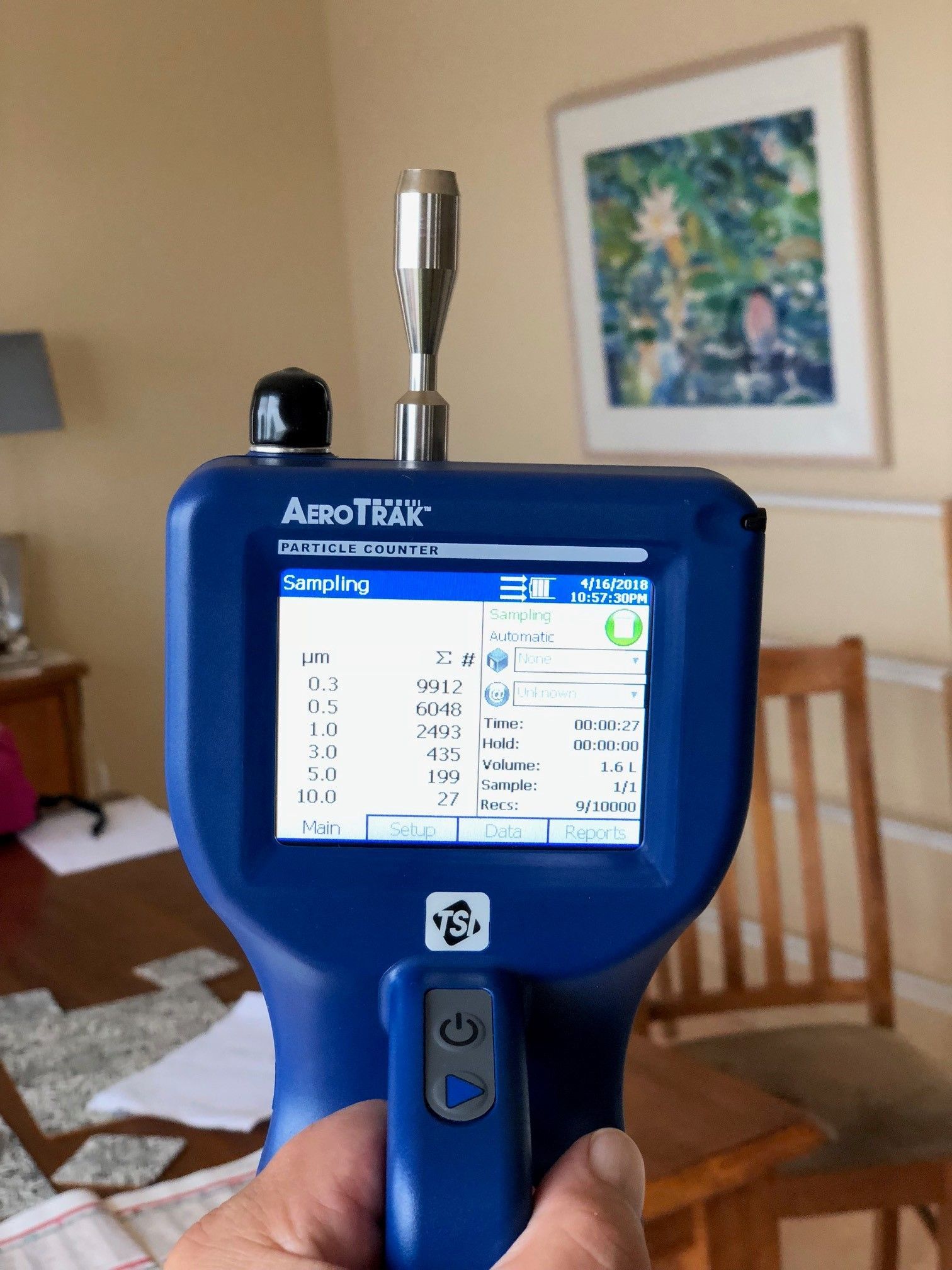 A woman is sitting on a couch in a living room with her hands behind her head.