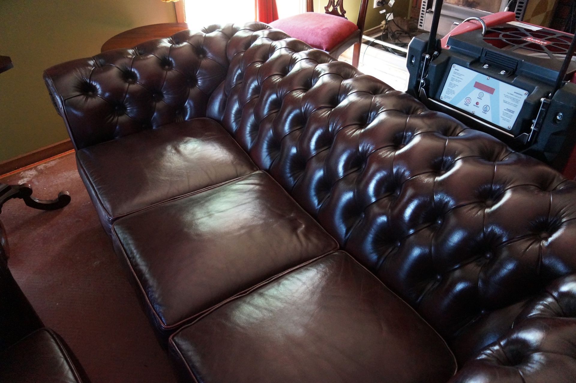 A person is cleaning a leather couch with a towel.