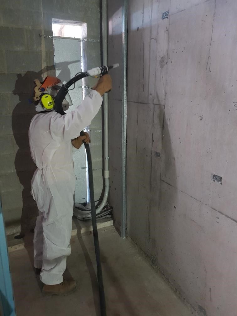 A construction worker wearing a blue hard hat is carrying a large piece of concrete.