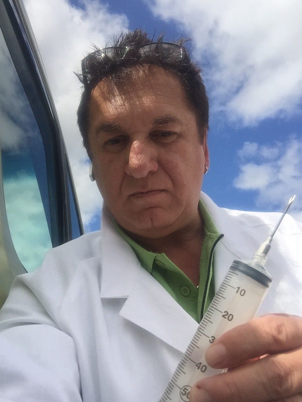 A man is putting on a yellow jacket with a hood in a hallway.