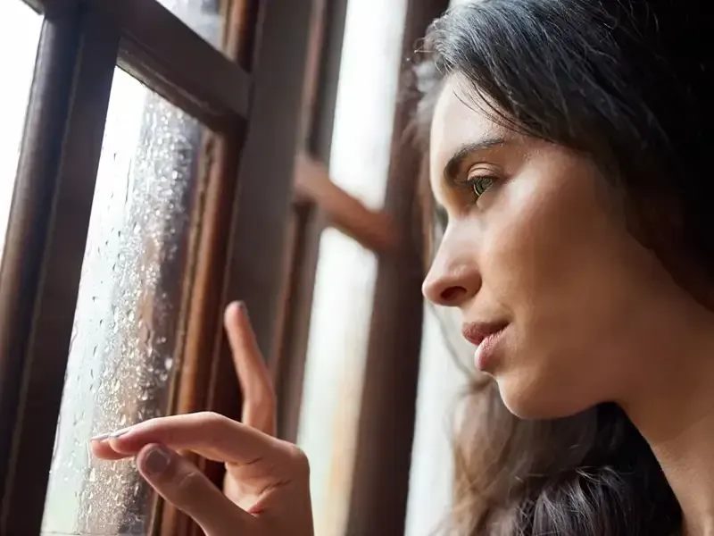 Woman looking through a window with Seasonal Affective Disorder. SAD therapy, NJ.