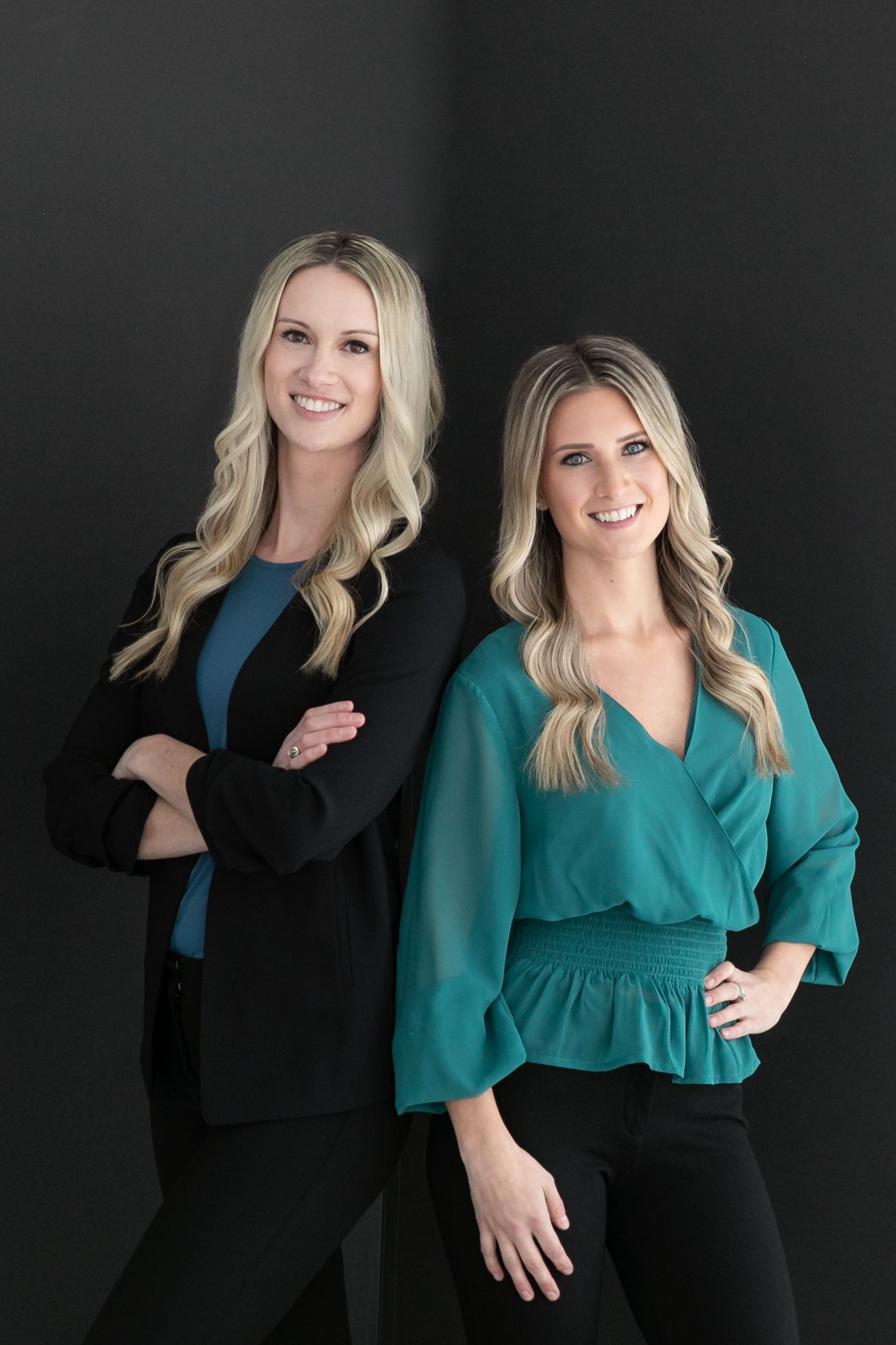 Two women are standing next to each other with their arms crossed.
