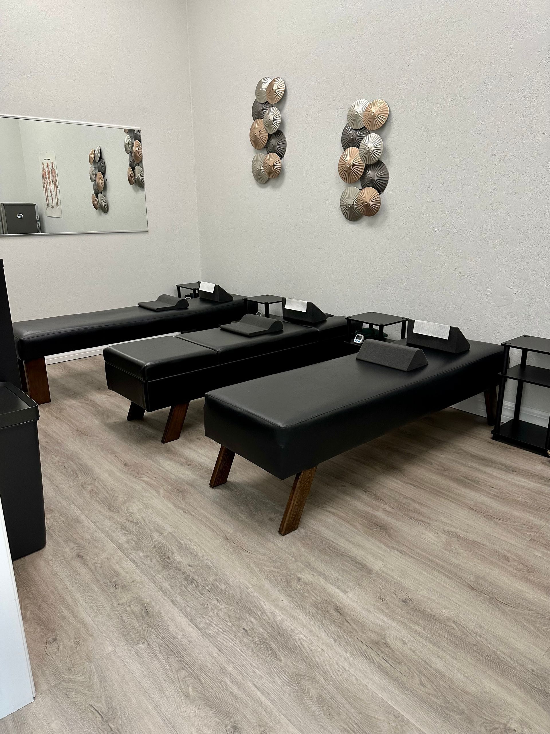 A room with three black beds and a mirror on the wall.