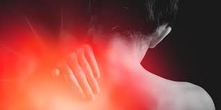 A woman is holding her neck in pain and there is a red light behind her.