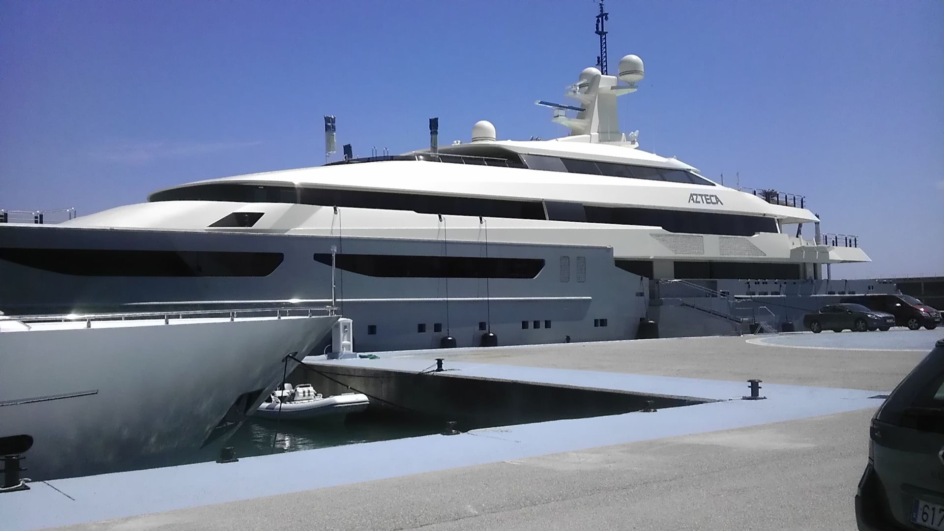 Un grande yacht bianco di lusso attraccato a un molo in una giornata di sole.