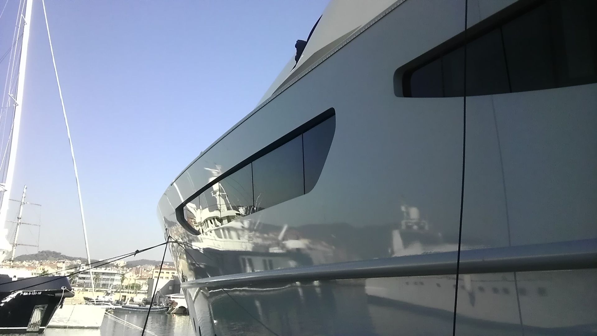 Lato bianco di uno yacht con vetri oscurati, ormeggiato in una giornata di sole.