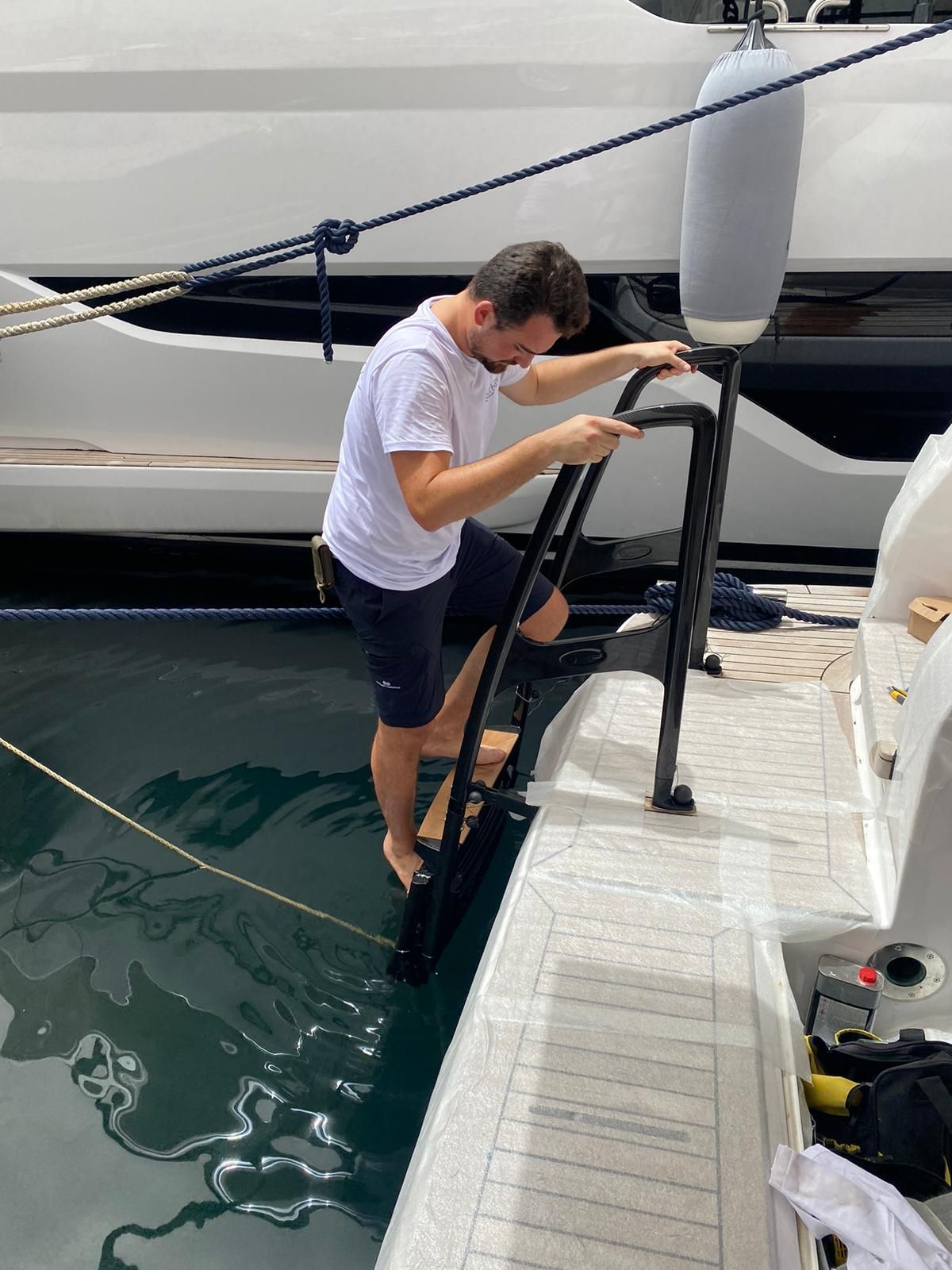 Uomo che sale su una barca bianca dall'acqua utilizzando una scala nera.