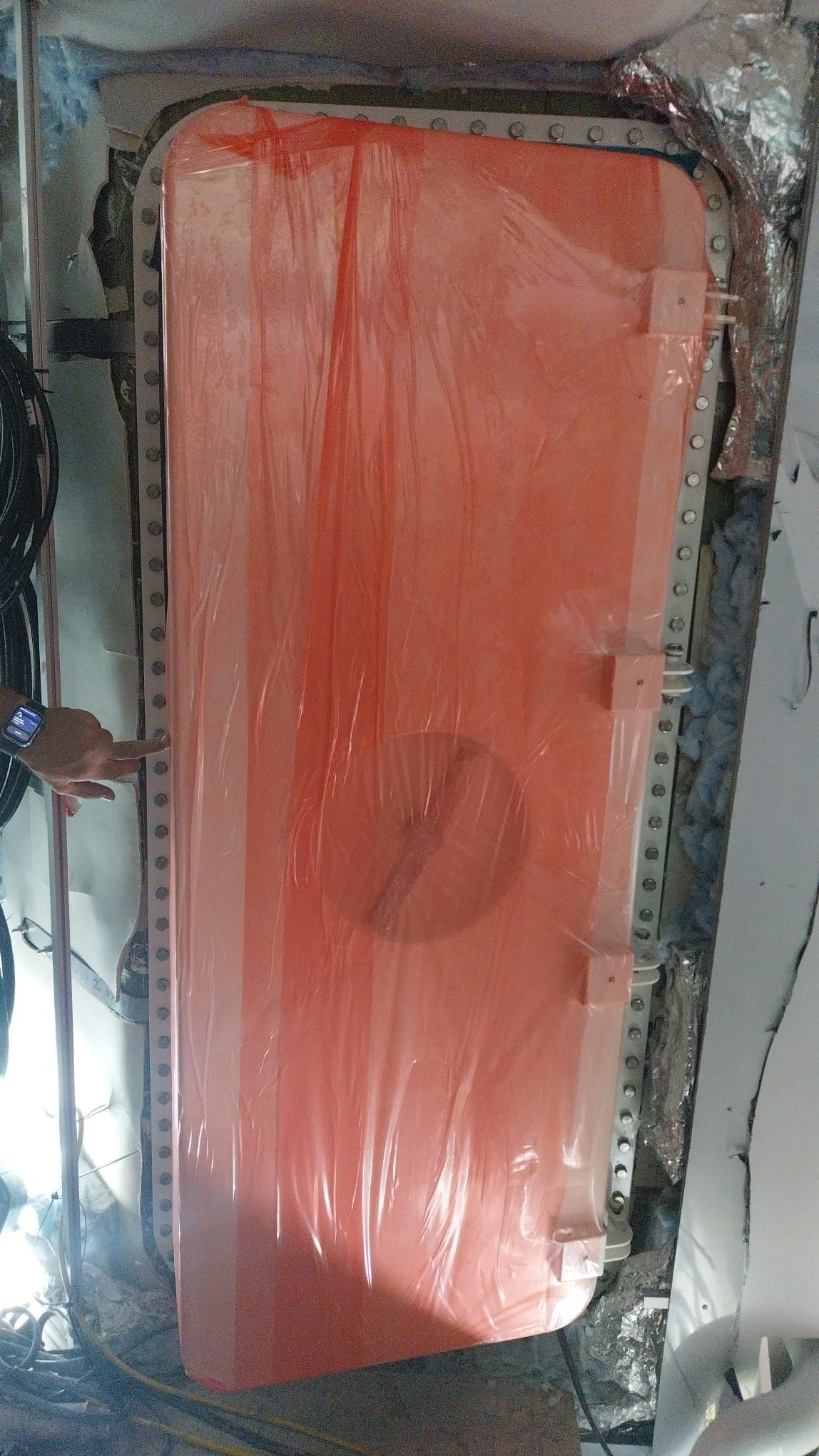 Porta arancione ricoperta di strisce rosse, probabilmente di sangue, in una cornice danneggiata.