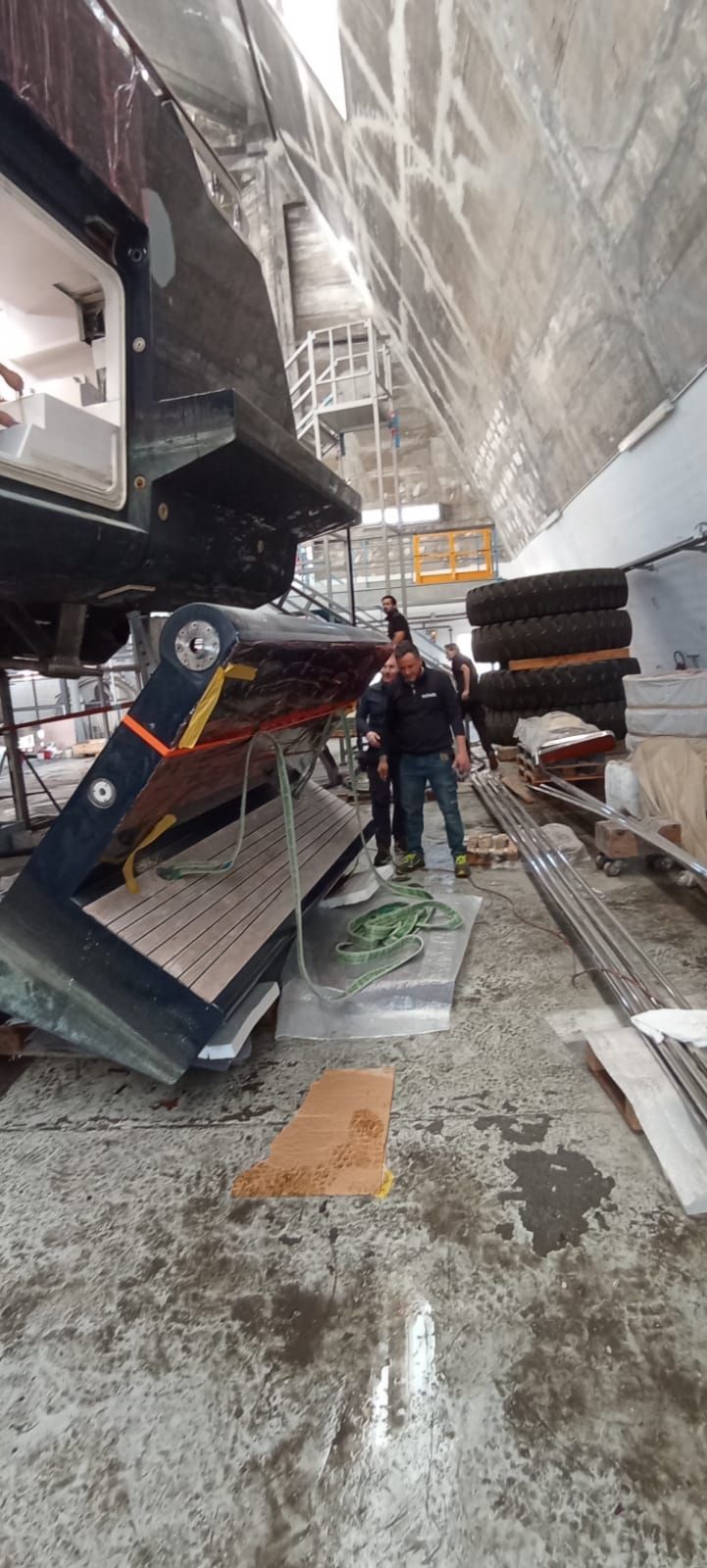 Uomo in piedi all'interno di una grande struttura vicino a una barca, probabilmente in costruzione.