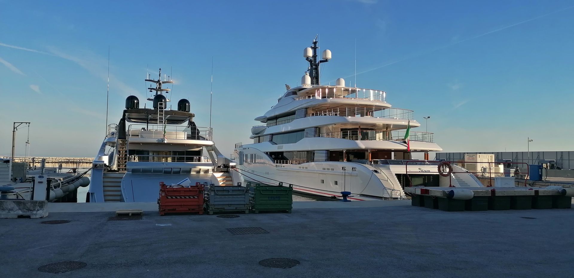 Due grandi yacht bianchi attraccano in un porto in una giornata limpida.