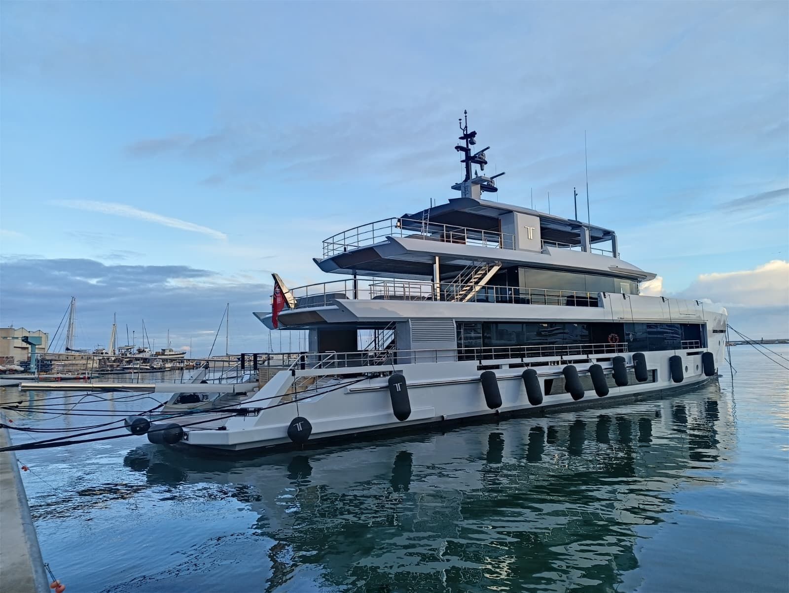 Uno yacht grigio attraccato in un porto in una giornata di sole.