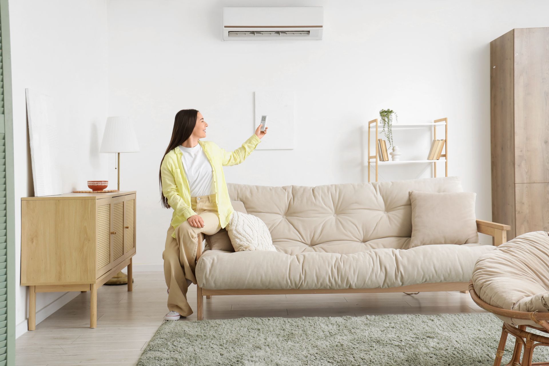 Three outdoor air conditioning units on a concrete pad with grass in the foreground.
