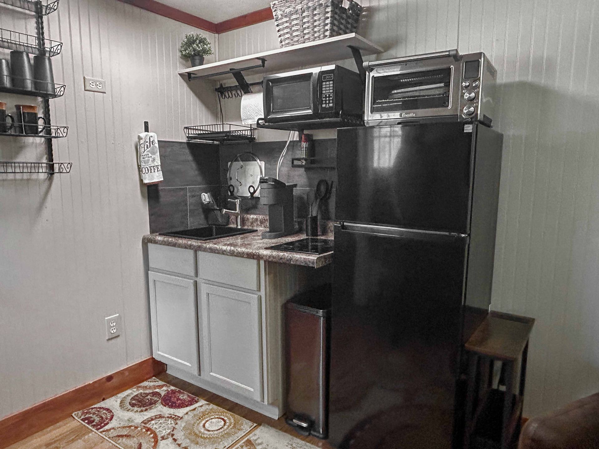 Small kitchen featuring a refrigerator, microwave, and toaster oven. A small sink area is visible.