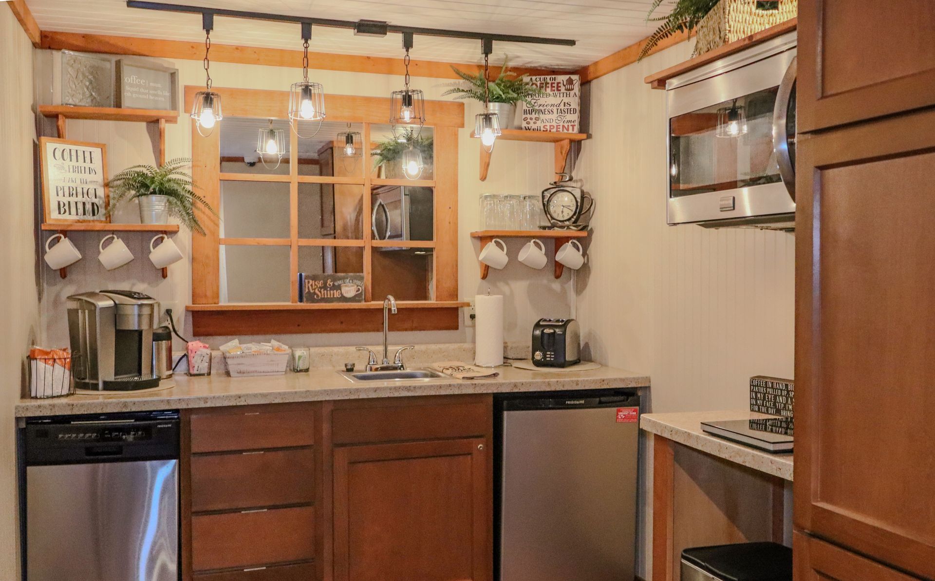 A small, cozy kitchen area with a stainless steel appliances and wooden cabinetry.