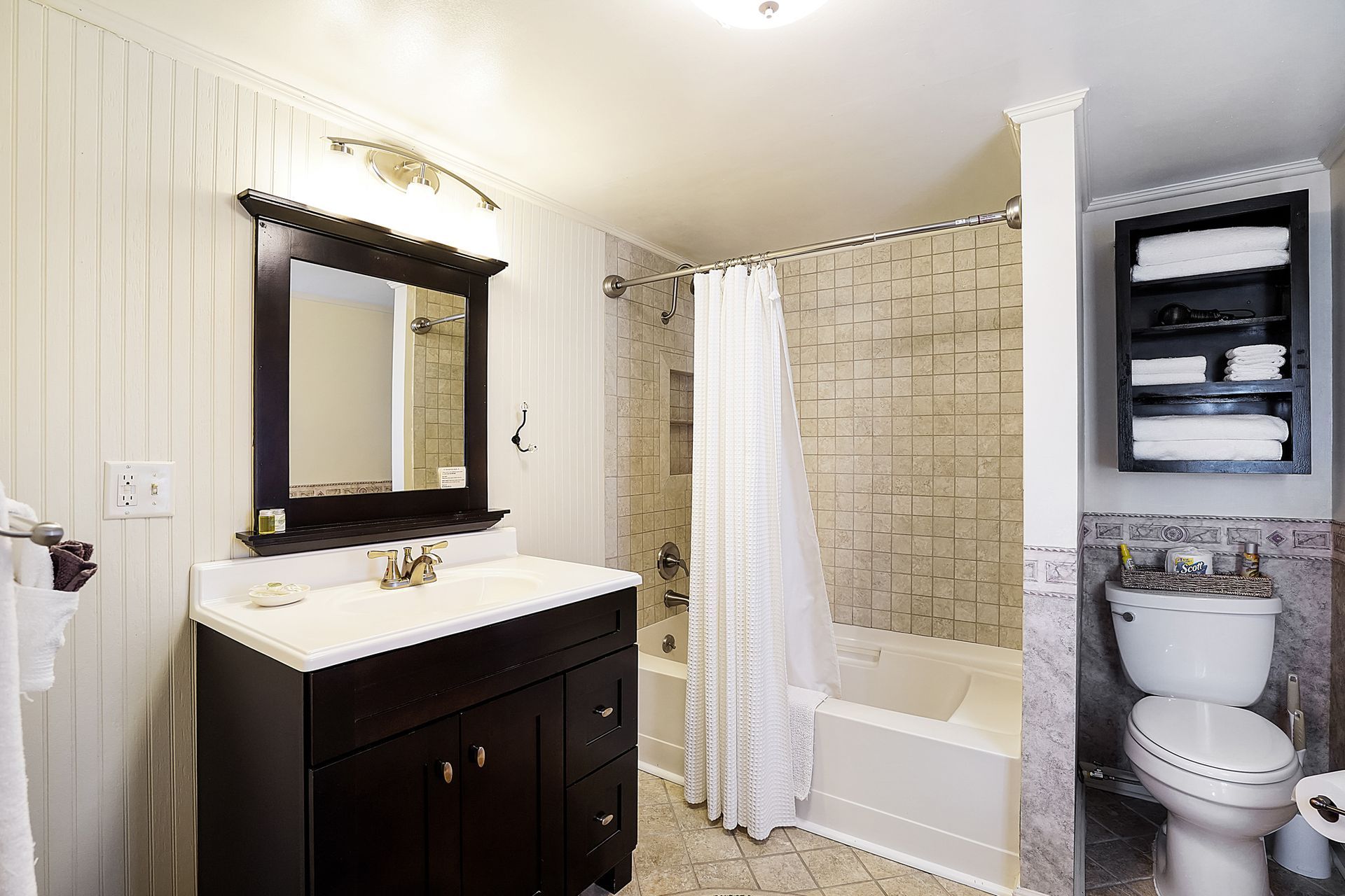 Bathroom with a vanity, bathtub with shower curtain, and toilet.