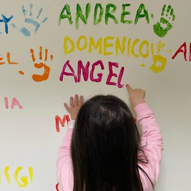 bambina scrive il suo nome sul muro