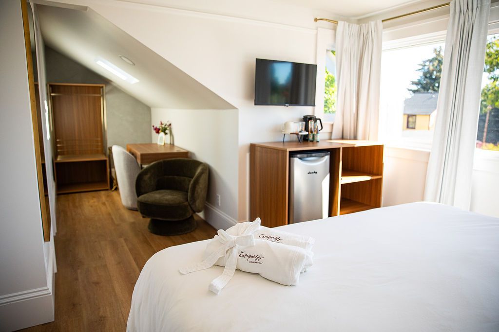A hotel room with a bed , chair , desk and television.