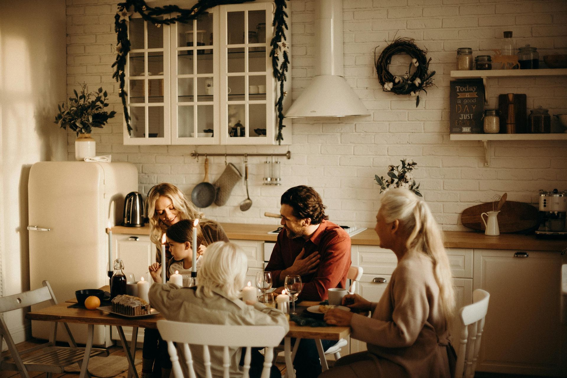 A family is sitting at a table in a kitchen eating food.