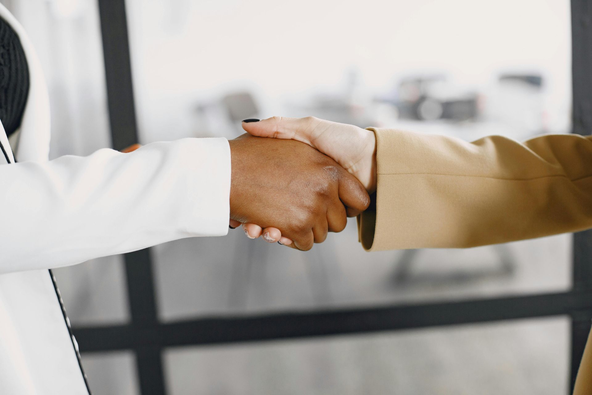 A man and a woman are shaking hands in an office.
