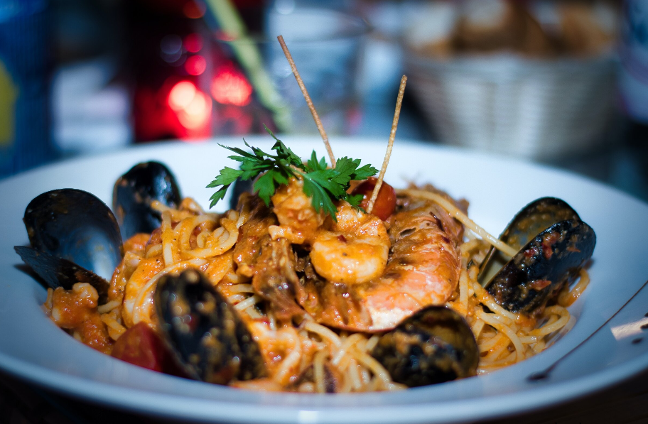 A plate of spaghetti with shrimp and mussels on a table.