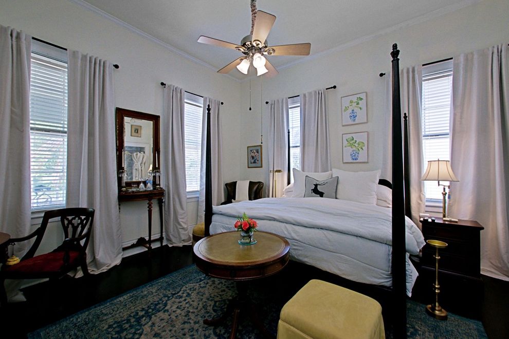 A bedroom with a four poster bed and a ceiling fan