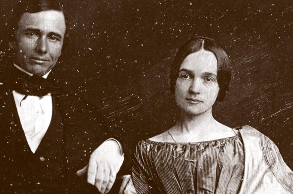 Sepia-toned portrait of a man and woman. Man wears a suit, woman a dress, both looking forward.