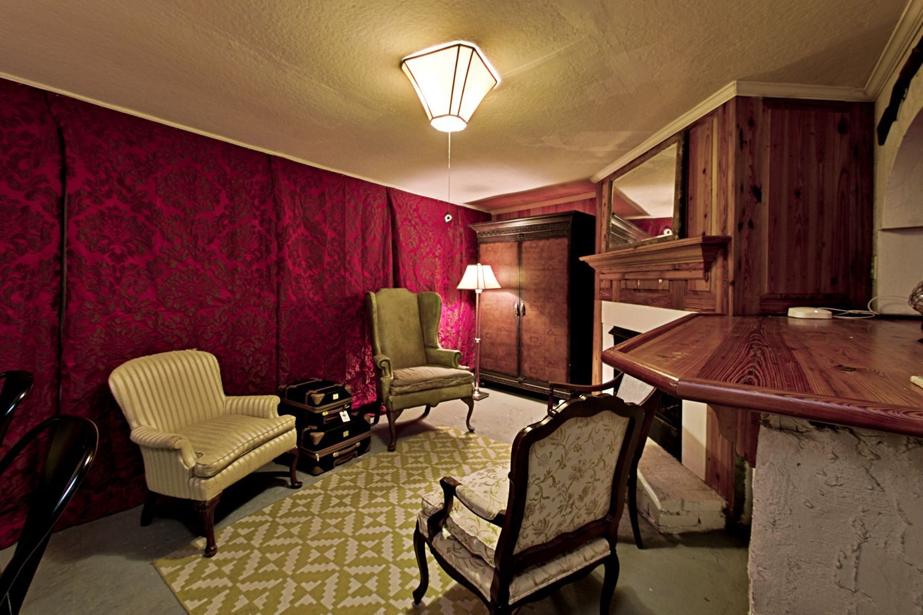 A cozy room with a red wall, patterned rug, and antique furniture.