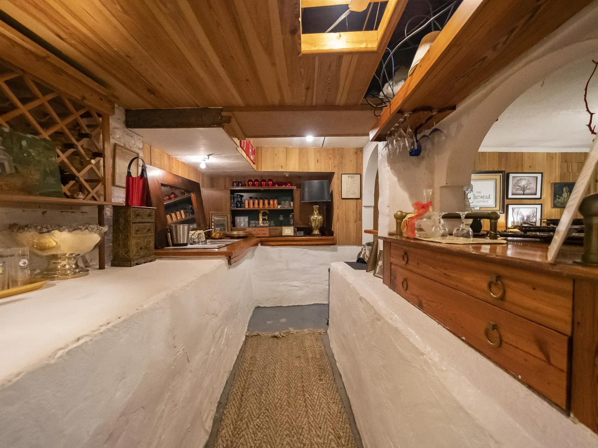 Wine cellar with wooden ceiling and walls, wine racks, bar, and stone walls.