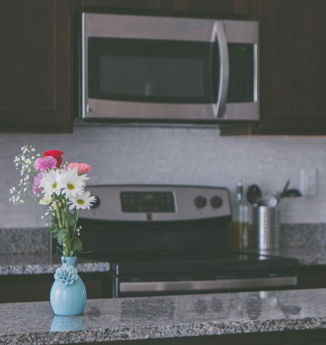 A kitchen counter with a vase of flowers on it