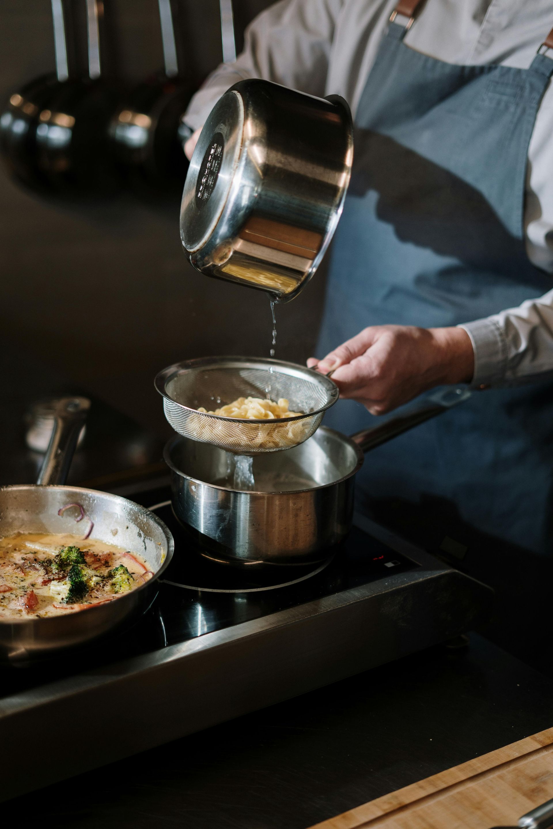 A man is cooking food in a pot on a stove.