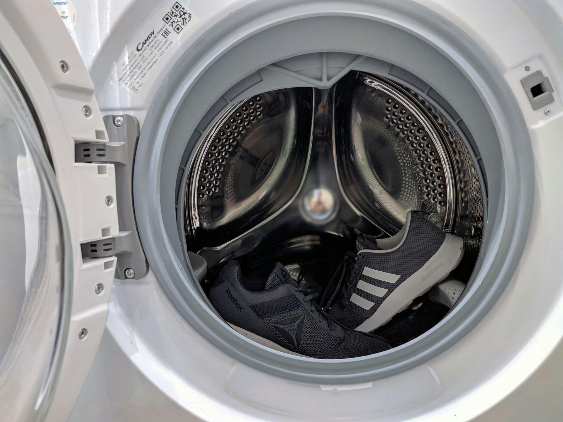 A pair of shoes is sitting inside of a washing machine.