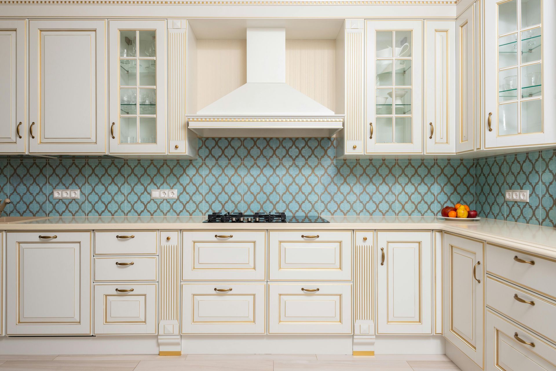 A kitchen with white cabinets and blue tiles on the wall.