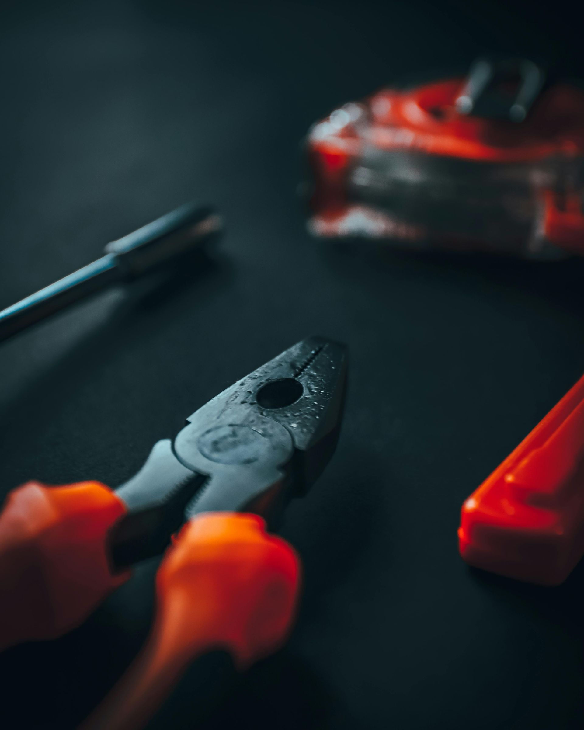 A pair of pliers and a screwdriver are on a table.