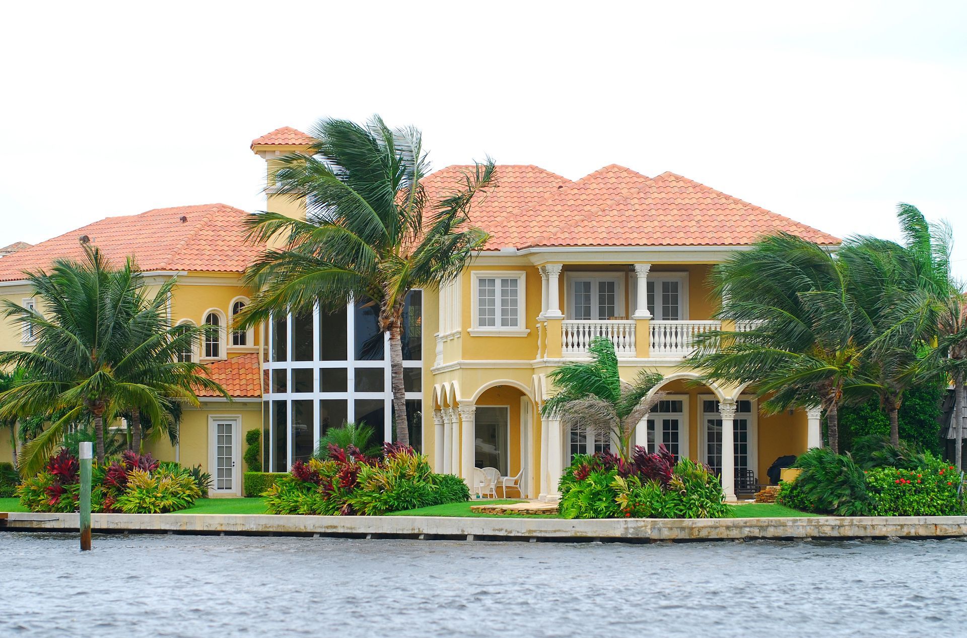 A large yellow house sits next to a body of water