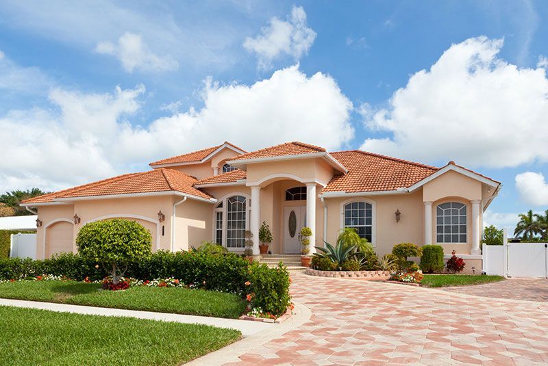 A large white house with a tiled roof and palm trees in front of it.