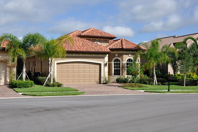 A large white house with a tiled roof and palm trees in front of it.