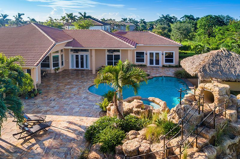 A large white house with a tiled roof and palm trees in front of it.