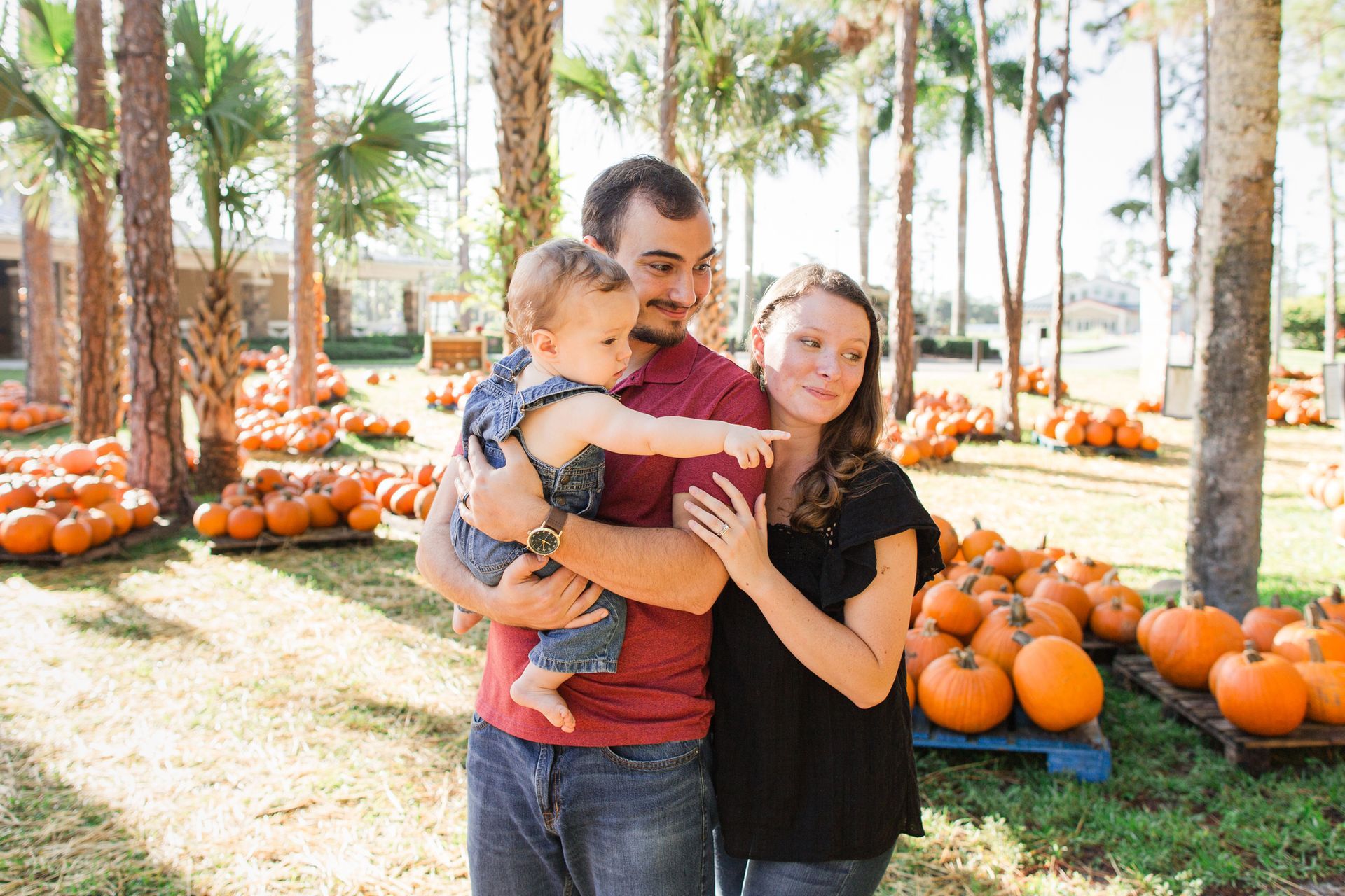 A family is posing for a picture at a pumpkin patch.