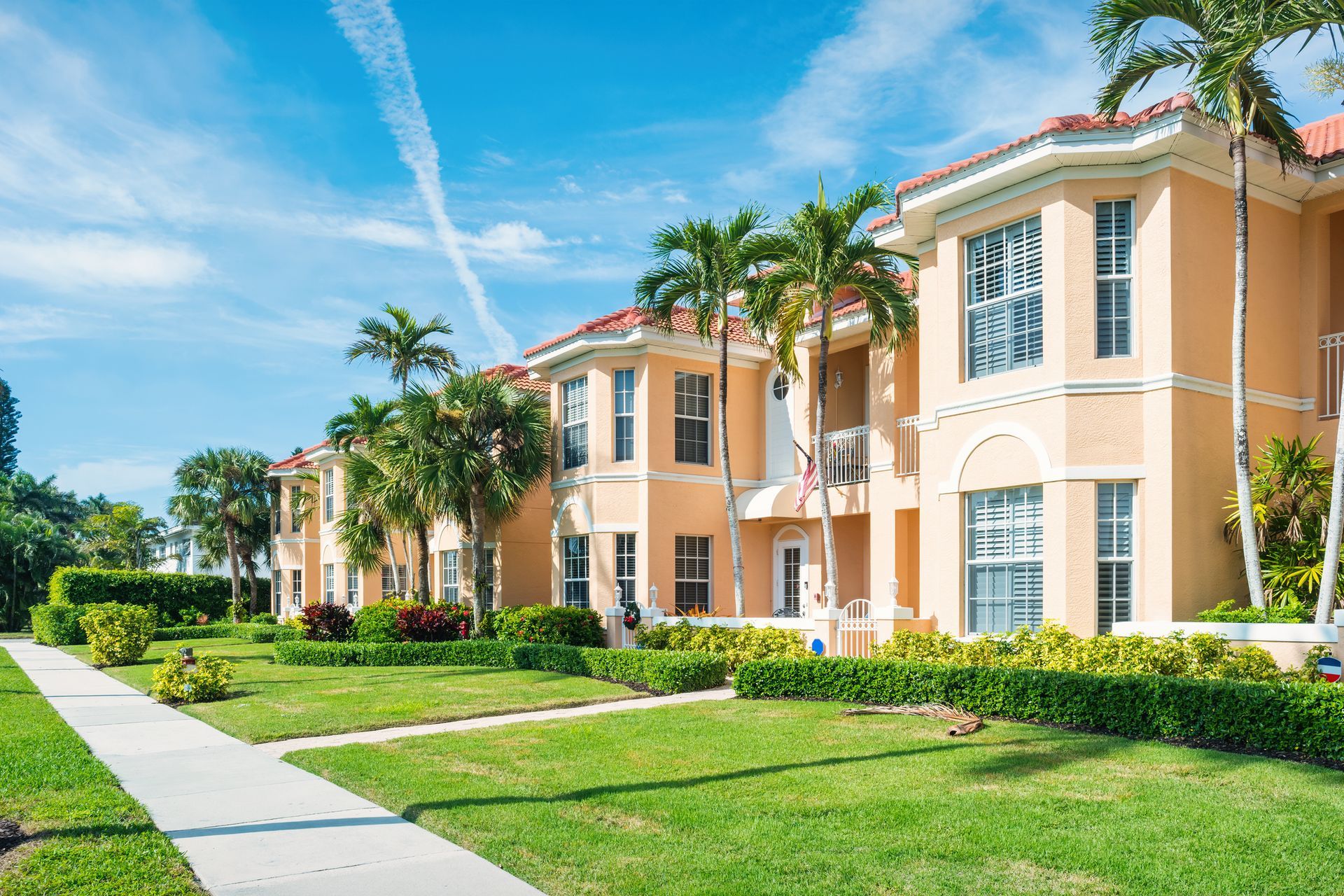 A row of apartment buildings with palm trees in a residential area.
