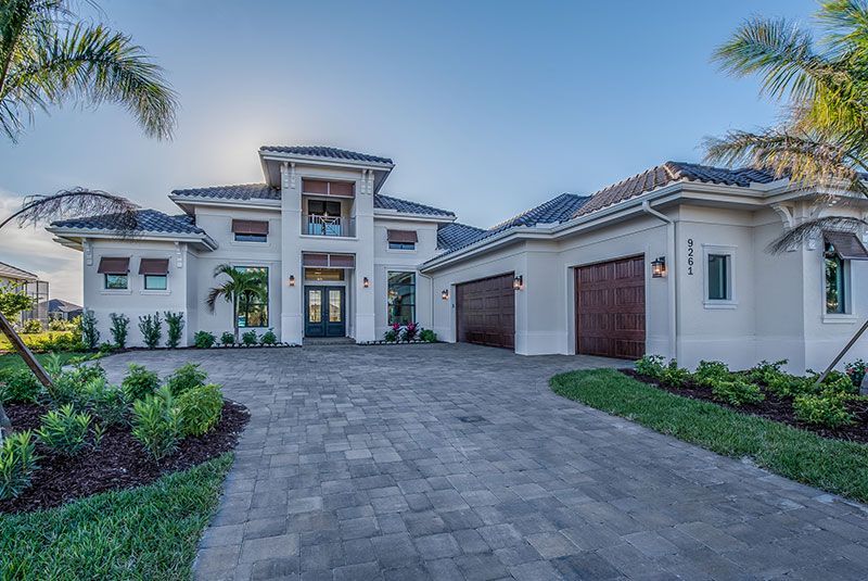 A large white house with a tiled roof and palm trees in front of it.