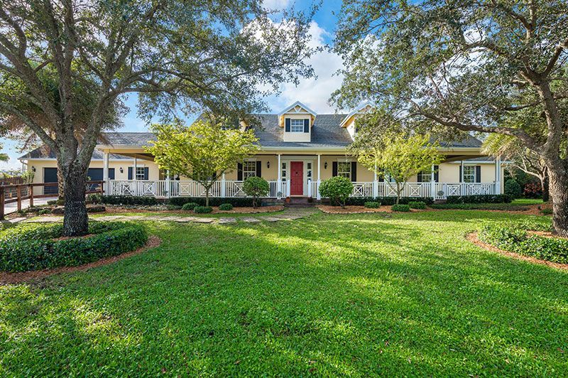 A large white house with a tiled roof and palm trees in front of it.